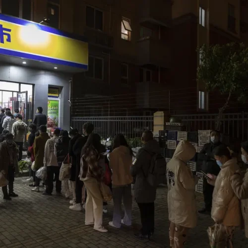 Gran cantidad de personas con mascarillas para protegerse del coronavirus hacen fila en un supermercado, el domingo 27 de marzo de 2022, en Shanghái, China. (AP Foto)